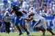 LEXINGTON, KY - SEPTEMBER 14: Jalen Whitlow #2 of the Kentucky Wildcats runs with the ball while defended by Preston Brown #2 of the Louisville Cardinals during the game at Commonwealth Stadium on September 14, 2013 in Lexington, Kentucky. (Photo by And