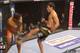 Machida throws a middle kick. Munoz dips to try and block it.