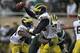 Nov 2, 2013; East Lansing, MI, USA; Michigan Wolverines quarterback Devin Gardner (98) tries to avoid a tackle from Michigan State Spartans defensive end Demetrius Cooper (98) during the third quarter at Spartan Stadium. Spartans beat the Wolverines 29-6.