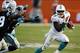 Nov 24, 2013; Miami Gardens, FL, USA; Miami Dolphins running back Lamar Miller (26) runs the ball around Carolina Panthers strong safety Robert Lester (38) in the second quarter of a game at Sun Life Stadium. Mandatory Credit: Robert Mayer-USA TODAY Spor