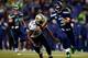 SEATTLE, WA - DECEMBER 02: Quarterback Russell Wilson #3 of the Seattle Seahawks runs with the ball as outside linebacker David Hawthorne #57 of the New Orleans Saints defends during a game at CenturyLink Field on December 2, 2013 in Seattle, Washington.