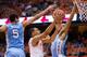 SYRACUSE, NY - JANUARY 11: Tyler Ennis #11 of the Syracuse Orange puts in a lay up between defenders Marcus Paige #5 and J.P. Tokoto #13 of the North Carolina Tar Heels in the first half on January 11, 2014 at The Carrier Dome in Syracuse, New York. (Pho