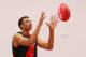 MELBOURNE, AUSTRALIA - FEBRUARY 14: Young Australian basketball player Dante Exum marks the ball after being presented a jumper by Joe Daniher of the Bombers during an Essendon Bombers AFL media session at True Value Solar Centre on February 14, 2014 in