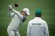AUGUSTA, GA - APRIL 07: (L-R) Rory McIlroy of Northern Ireland hits a shot as his caddie, J. P. Fitzgerald, looks on during a practice round prior to the start of the 2014 Masters Tournament at Augusta National Golf Club on April 7, 2014 in Augusta, Geor