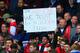LONDON, ENGLAND - MARCH 22: Arsenal fans hold up a sign to mark Arsene Wenger manager of Arsenal's 1000th game during the Barclays Premier League match between Chelsea and Arsenal at Stamford Bridge on March 22, 2014 in London, England. (Photo by Richard