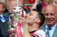 LONDON, ENGLAND - MAY 17: Captain Thomas Vermaelen of Arsenal (R) kisses the trophy in celebration as FA chairman Greg Dyke looks on after the FA Cup with Budweiser Final match between Arsenal and Hull City at Wembley Stadium on May 17, 2014 in London, E
