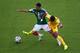 NATAL, BRAZIL - JUNE 13: Enoh Eyong of Cameroon challenges Jose Juan Vazquez of Mexico in the first half during the 2014 FIFA World Cup Brazil Group A match between Mexico and Cameroon at Estadio das Dunas on June 13, 2014 in Natal, Brazil. (Photo by Mig