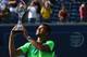TORONTO, ON - AUGUST 10: Jo-Wilfried Tsonga of France holds up the Rogers Cup trophy after his win against Roger Federer of Switzerland during Rogers Cup at Rexall Centre at York University on August 10, 2014 in Toronto, Canada. (Photo by Ronald Martine