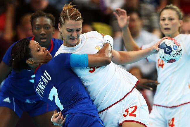 Montenegro's Katarina Bulatovic, center, wrestles France's Allison Pineau away before attempting a shot at goal.