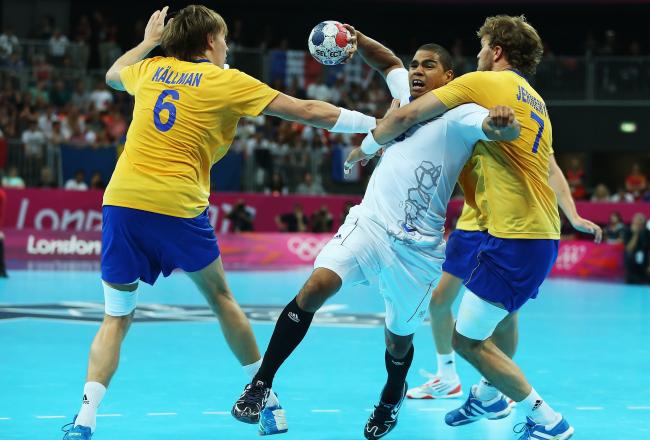 France's Daniel Narcisse, center, fights off the Swedish defense en route to a 23-22 win to keep the Olympic title.