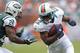 MIAMI GARDENS, FL - SEPTEMBER 23: Reggie Bush #22 of the Miami Dolphins runs with the ball against Darrelle Revis #24 of the New York Jets on September 23, 2012 at Sun Life Stadium in Miami Gardens, Florida. The Jets defeated the Dolphins 23-20 in overtime. (Photo by Joel Auerbach/Getty Images)