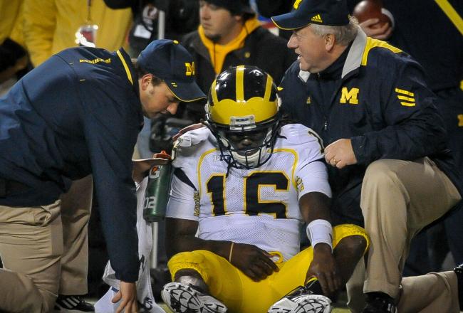 Coaches aide Denard Robinson after a tough fall that reportedly caused nerve problems in his right elbow.