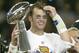 HOUSTON, TX - FEBRUARY 1: MVP Tom Brady #12 of the New England Patriots raises the Lombardi trophy as he is interviewed by television commentator Jim Nance after defeating the Carolina Panthers 32-29 in Super Bowl XXXVIII at Reliant Stadium on February 1, 2004 in Houston, Texas. (Photo by Elsa/Getty Images)