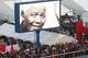 DURBAN, SOUTH AFRICA - JULY 06: A giant screen projects images of former president Nelson Mandela during the 2013 Vodacom Durban July at Greyville Racecourse on July 06, 2013 in Durban, South Africa. The main race of the day, the President's Champions Challenge, was won for the first time by a black jockey; S'manga Khumalo riding Heavy Metal. As a tribute to former president Nelson Mandela, who remains critically ill in hospital, sixty seven seconds of silence were observed. (Photo by Anesh Debiky/Gallo Images/Getty Images)