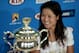 Li Na of China smiles beside the championship trophy, during a press conference, after defeating Dominika Cibulkova of Slovakia in their women's singles final at the Australian Open tennis championship in Melbourne, Australia, Saturday, Jan. 25, 2014.(AP Photo/Rick Rycroft)