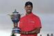 Tiger Woods holds the Gene Sarazen Cup for winning the Cadillac Championship golf tournament on Sunday, March 10, 2013, in Doral, Fla. (AP Photo/Wilfredo Lee)