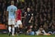 Manchester United's Marouane Fellaini, center left, reacts after receiving a yellow card from referee Michael Oliver for a challenge on Manchester City's Pablo Zabaleta, bottom, during their English Premier League soccer match at Old Trafford Stadium, Manchester, England, Tuesday, March 25, 2014. (AP Photo/Jon Super)