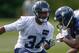 Seattle Seahawks rookie Tharold Simon smiles as he carries gear for teammates following practice at NFL football training camp Tuesday, Aug. 6, 2013, in Renton, Wash. (AP Photo/Elaine Thompson)