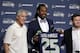 Seattle Seahawks' Richard Sherman, center, holds up a jersey before a news conference as he poses with head coach Pete Carroll, left, and general manager John Schneider Wednesday, May 7, 2014, at the team's headquarters in Renton, Wash. Sherman signed a four-year contract extension Wednesday with the Seahawks, a deal that makes him one of the highest-paid cornerbacks in NFL history. (AP Photo/Elaine Thompson)