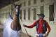 Exercise rider Willie Delgado laughs as he walks California Chrome around the stables after he jogged around the track at Belmont Park in Elmont, N.Y., Wednesday, May 21, 2014. California Chrome arrived in New York on Tuesday to begin preparations for his bid to become horse racing's first Triple Crown winner in 36 years. (AP Photo/Seth Wenig)