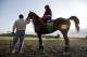 Assistant trainer Alan Sherman, left, leads exercise rider Willie Delgado and California Chrome onto the track at Belmont Park in Elmont, N.Y., Wednesday, May 21, 2014. California Chrome arrived in New York on Tuesday to begin preparations for his bid to become horse racing's first Triple Crown winner in 36 years. (AP Photo/Seth Wenig)