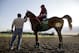 Assistant trainer Alan Sherman, left, leads exercise rider Willie Delgado and California Chrome onto the track at Belmont Park in Elmont, N.Y., Wednesday, May 21, 2014. California Chrome arrived in New York on Tuesday to begin preparations for his bid to become horse racing's first Triple Crown winner in 36 years. (AP Photo/Seth Wenig)