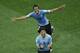 Uruguay's Luis Suarez, front, is chased by his teammate Alvaro Gonzalez as he celebrates scoring the opening goal during the group D World Cup soccer match between Uruguay and England at the Itaquerao Stadium in Sao Paulo, Brazil, Thursday, June 19, 2014. (AP Photo/Michael Sohn)