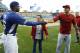 Los Angeles Dodgers' Yasiel Puig, left, shakes hands with Los Angeles Angels' Mike Trout, right, after they talked with jockey Victor Espinoza, center, before Espinoza threw out the first pitch for an exhibition baseball game in Los Angeles, Thursday, March 27, 2014. (AP Photo/Danny Moloshok)