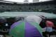Spectators sit under umbrellas as rain falls and play is suspended on No 1 Court in the match between Grigor Dimitrov of Bulgaria and Leonardo Mayer of Argentina at the All England Lawn Tennis Championships in Wimbledon, London, Monday, June 30, 2014. (AP Photo/Ben Curtis)