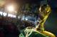 Brazilian residents watch the opening match of FIFA World Cup between Brazil and Croatia behind a replica of the trophy in Porto Seguro, Brazil, Thursday, June 12, 2014. (AP Photo/Matthias Schrader)