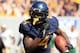 West Virginia's Wendell Smallwood (4) carries the ball during the fourth quarter of their NCAA college football game against William and Mary in Morgantown, W.Va., on Saturday, Aug. 31, 2013. West Virginia won 24-17. (AP Photo/Christopher Jackson)