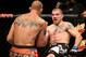 Jul 16, 2014; Atlantic City, NJ, USA; A bloodied Jim Miller (blue gloves) kicks at Donald Cerrone (red gloves) during a 5-round lightweight bout at Revel Casino. Mandatory Credit: Bill Streicher-USA TODAY Sports