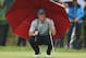 Rory McIlroy of Northern Ireland kneels under an umbrella as he waits to play on the 4th green during the third day of the British Open Golf championship at the Royal Liverpool golf club, Hoylake, England, Saturday July 19, 2014. (AP Photo/Jon Super)