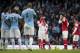 Arsenal's Mesut Ozil, centre, wipes his face as he waits for play to restart after Manchester City's fourth goal during their English Premier League soccer match at the Etihad Stadium, Manchester, England, Saturday Dec. 14, 2013. (AP Photo/Jon Super)