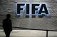 TOPSHOT - A FIFA employee walks past a sign of the FIFA at the headquarters on December 3, 2015 in Zurich.
The unprecedented corruption scandal engulfing FIFA widened on December 3 with the arrests of two more top officials in another dramatic dawn raid at a luxury hotel in Zurich. / AFP / FABRICE COFFRINI (Photo credit should read FABRICE COFFRINI/AFP/Getty Images)