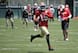 49ers head coach Jim Harbaugh watches intently in the background at star wideout Michael Crabtree during a May OTA.