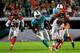 MIAMI GARDENS, FL - OCTOBER 31: (C) Lamar Miller #26 of the Miami Dolphins runs with ball under pressure from (L) Reggie Nelson #20 of the Cincinnati Bengals and (R) Carlos Dunlap #96 of the Cincinnati Bengals at Sun Life Stadium on October 31, 2013 in Mi