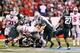INDIANAPOLIS, IN - DECEMBER 07: Carlos Hyde #34 of the Ohio State Buckeyes is tackled by the defense of the Michigan State Spartans during the Big Ten Conference Championship game at Lucas Oil Stadium on December 7, 2013 in Indianapolis, Indiana. (Photo