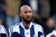 LONDON, ENGLAND - DECEMBER 28: Nicolas Anelka of West Brom touches his sleeve as he celebrates scoring their first goal during the Barclays Premier League match between West Ham United and West Bromwich Albion at Boleyn Ground on December 28, 2013 in Lon