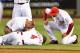 CINCINNATI, OH - JULY 9: Athletic trainer Steve Baumann of the Cincinnati Reds attends to Brandon Phillips #4 of the Cincinnati Reds and Manager Bryan Price #38 of the Cincinnati Reds watches after Phillips injured his thumb diving for a ball in the eight