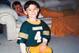 Dylan Favre in Uncle Brett's Packers jersey as his father Jeff rests on the couch.