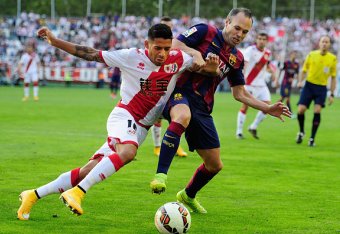 MADRID, SPAIN - OCTOBER 04:  Andres Iniesta of FC Barcelona is tackled by Javier Ignacio Aquino of Rayo Vallecano de Madrid during the La Liga match between Rayo Vallecano de Madrid and FC Barcelona at Estadio Teresa Rivero on October 4, 2014 in Madrid, S
