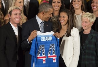 The US 2015 Women's World Cup Team's Abby Wambach (L) and Carli Lloyd (2nd R) present US President Barack Obama (C) with a team jersey during an event honoring them at the White House in Washington, DC, October 27, 2015.    AFP PHOTO / JIM WATSON        (