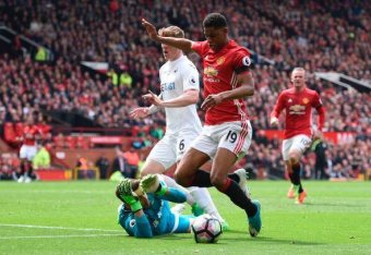 Manchester United's English striker Marcus Rashford (R) goes down uner a challenge from Swansea City's Polish goalkeeper Lukasz Fabianski (L) to earn a penalty during the English Premier League football match between Manchester United and Swansea City at