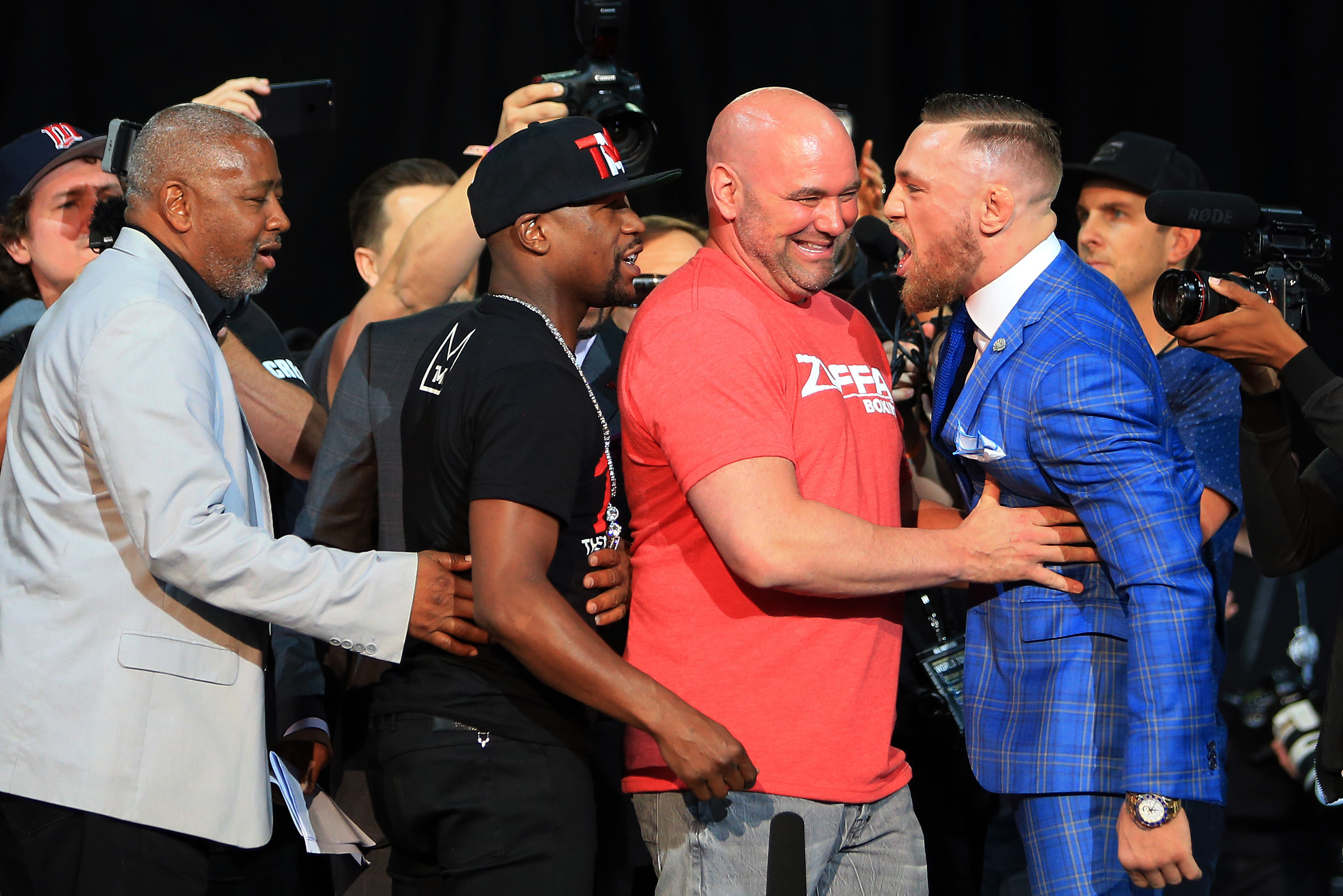 White holds McGregor back during a pre-fight news conference with Mayweather.
