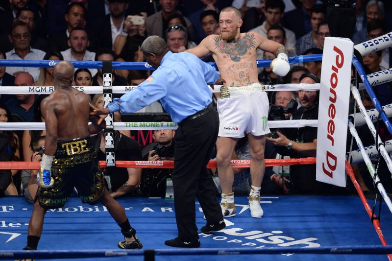 McGregor hands out on the ropes as referee Robert Byrd moves Mayweather back.