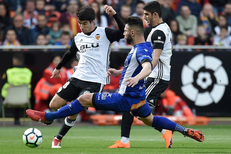 Deportivo Alaves' defender Ruben Duarte (C) vies with Valencia's midfielder Carlos Soler (L) during the Spanish League football match between Valencia CF and Deportivo Alaves at the Mestalla stadium in Valencia on March 17, 2018. / AFP PHOTO / JOSE JORDAN