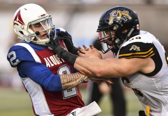 MONTREAL, QC - AUGUST 03:  Defensive end Jason Neill #96 of the Hamilton Tiger-Cats (R) defends against quarterback Johnny Manziel #2 of the Montreal Alouettes (L) during the CFL game at Percival Molson Stadium on August 3, 2018 in Montreal, Quebec, Canad