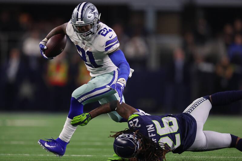 ARLINGTON, TEXAS - JANUARY 05: Ezekiel Elliott #21 of the Dallas Cowboys breaks a tackle attempt by Shaquill Griffin #26 of the Seattle Seahawks in the fourth quarter during the Wild Card Round at AT&T Stadium on January 05, 2019 in Arlington, Texas. (Pho