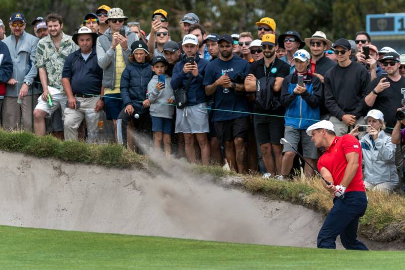 US player Bryson DeChambeau (R) plays out of the bunker to the 17th hole on the last day of the Presidents Cup golf tournament in Melbourne on December 15, 2019. (Photo by SIMON BAKER / AFP) / -- IMAGE RESTRICTED TO EDITORIAL USE - STRICTLY NO COMMERCIAL